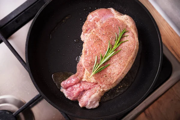 Kızarmış tavada biberiyeli domuz bifteği. Mutfakta ocakta et pişiriyorum..