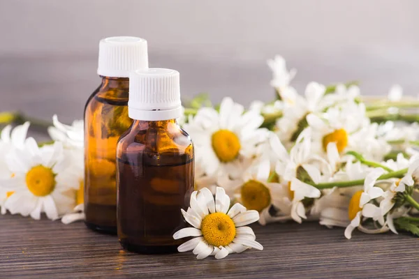 Cam şişe, ahşap bir masada çiçekli papatya yağı aromalı. Kozmetik ve tıbbi organik konsept.