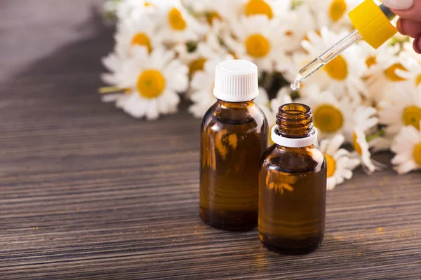 Cam şişe, ahşap bir masada çiçekli papatya yağı aromalı. Kozmetik ve tıbbi organik konsept.