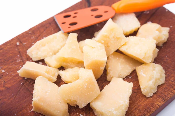 Beyaz arka planda izole edilmiş tahta kesim tahtasındaki parmesan peyniri parçaları.