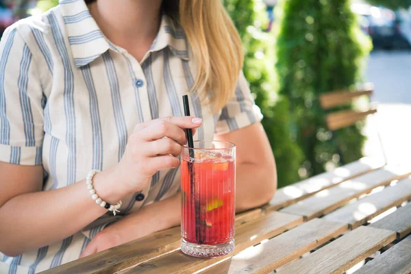 Genç ve güzel bir kız kafedeki ahşap masada soğuk içecek kokteyli içiyor. Yaz yaşam tarzı insanları.