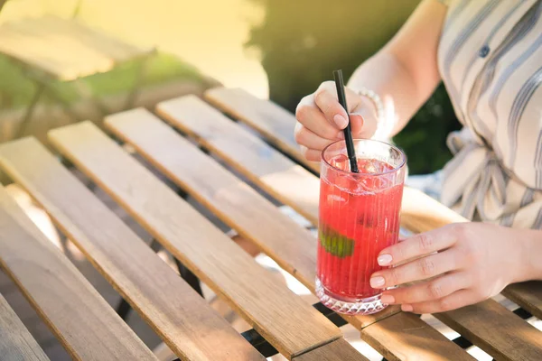 Genç ve güzel bir kız kafedeki ahşap masada soğuk içecek kokteyli içiyor. Yaz yaşam tarzı insanları.
