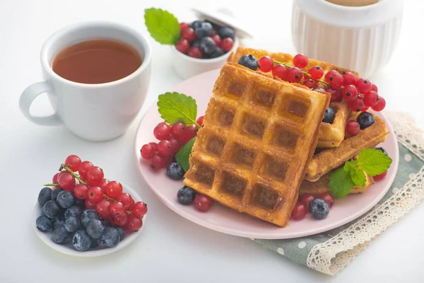 Böğürtlenli, üzümlü ve üzümlü tatlı Belçika waffle 'ı ve beyaz arka planda çay içeceği. Lezzetli kalori kahvaltısı..