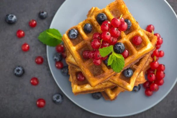 Yaban mersinli, üzümlü ve üzümlü tatlı Belçika waffle 'ı. Taş bir masada yeşil nane. Lezzetli bir sabah kahvaltısı. en üstteki görünüm
