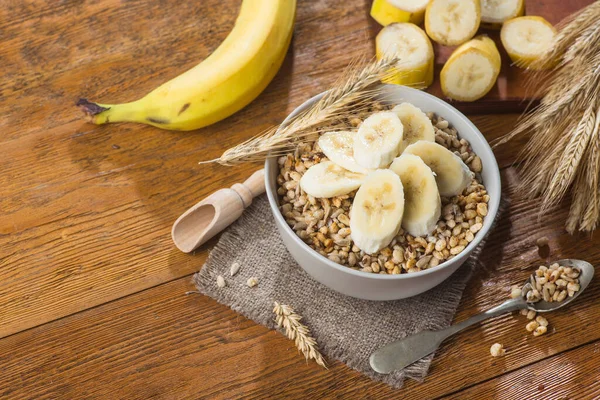 Tohum ve buğdaylı kasede gevrek gevrek, ahşap bir masada muz. Kaba, sağlıklı kahvaltılık mısır gevreği. Üst Manzara. metin için boşluk kopyala