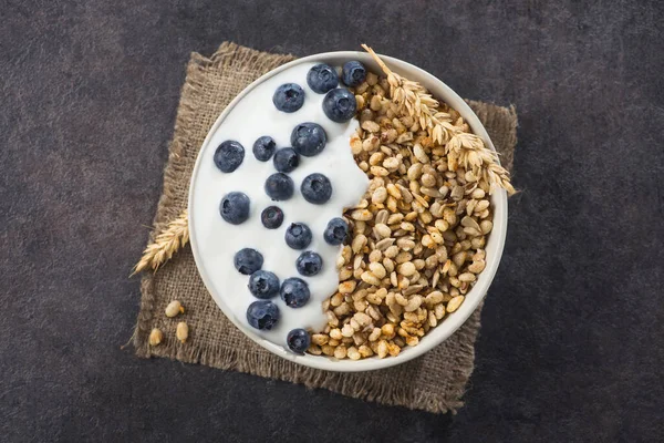 Bir kase ev yapımı gevrek yoğurt, taze yaban mersini ve arkaplanda buğday tohumu. Sağlıklı sabah kahvaltısı. Üst Manzara. metin için boşluk kopyala