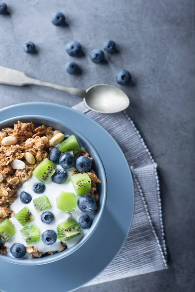 Mısır gevreğiyle sağlıklı kahvaltı yabanmersinli, kivili, yoğurtlu ve mavi kasede yer fıstıklı. Günaydın tatlı tatlı atıştırmalık. en üstteki görünüm