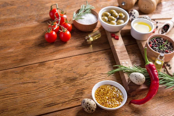 Taze salata malzemeleri (tuz, biber, zeytin, domates, biberiye, yağ) ahşap bir masa üzerinde kesme tahtasıyla birlikte. metin için boşluk kopyala