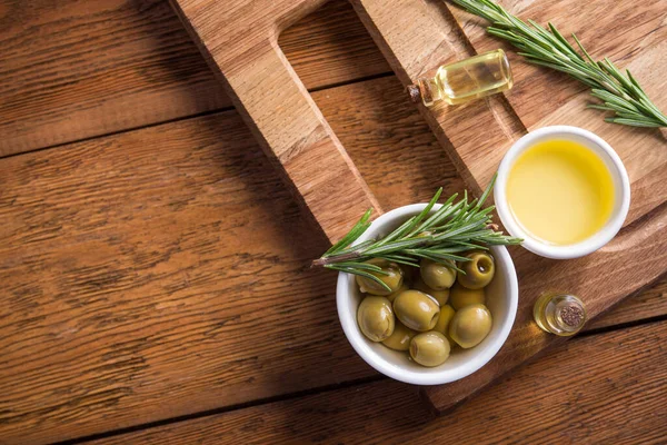 Biberiye bitkisi ve zeytinyağını ahşap bir masanın arka planında bir kaseye koy. Üst Manzara. metin için boşluk kopyala