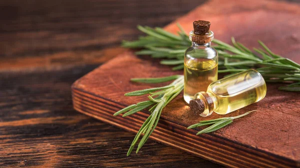 Closeup of  rosemary herb oil in a small glass bottle on a wooden table