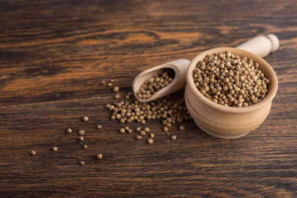 Masadaki ahşap kasede kişniş tohumları.