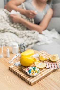 Soğuk algınlığı ve grip olan genç bir kadın. Evde kendi kendini tedavi ediyor. Vitamin ve haplarla. Alerji yüzünden burnu ağrıyor..