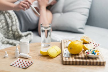 Soğuk algınlığı ve grip olan genç bir kadın. Evde kendi kendini tedavi ediyor. Vitamin ve haplarla. Alerji yüzünden burnu ağrıyor..