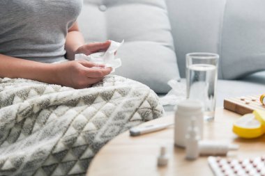 Soğuk algınlığı ve grip olan genç bir kadın. Evde kendi kendini tedavi ediyor. Vitamin ve haplarla. Alerji yüzünden burnu ağrıyor..