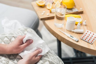 Soğuk algınlığı ve grip olan genç bir kadın. Evde kendi kendini tedavi ediyor. Vitamin ve haplarla. Alerji yüzünden burnu ağrıyor..