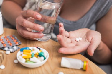 Soğuk algınlığı ve grip olan genç bir kadın. Evde kendi kendini tedavi ediyor. Vitamin ve haplarla. Alerji yüzünden burnu ağrıyor..