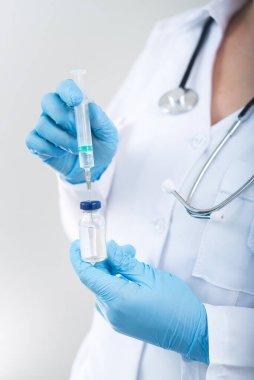 Kadın doktor elinde grip aşısı ve şırıngayla beyaz bir zemin tutuyor. Elinde tıbbi enjeksiyon ve aşılama.