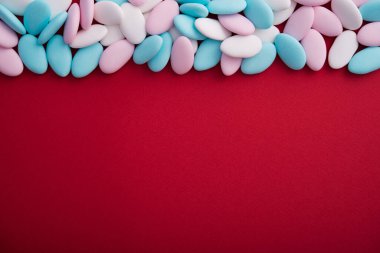 Kırmızı arka planda mavi, beyaz ve pembe spa taşları. Asgari bir dizaynda soyut desen. Pastel renk. Düz Yat. Üst görünüm.