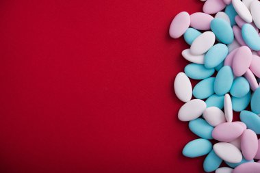 Kırmızı arka planda mavi, beyaz ve pembe spa taşları. Asgari bir dizaynda soyut desen. Pastel renk. Düz Yat. Üst görünüm.