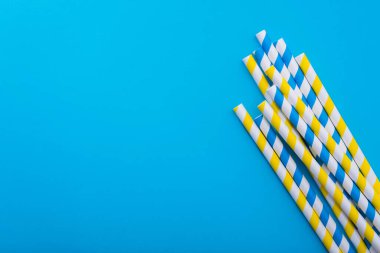 Mavi arka planda parlak renkli kokteyl pipeti. Geri dönüşüm ekosu konsepti. En az stil. Düz yat. üstte