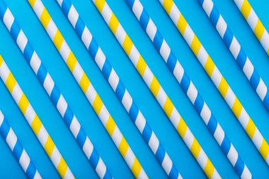 Mavi arka planda parlak renkli kokteyl pipeti. Geri dönüşüm ekosu konsepti. En az stil. Düz yat. üstte