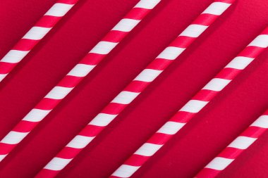 Kırmızı arka planda parlak renkli kokteyl pipeti. Geri dönüşüm ekosu konsepti. En az stil. Düz yat. üstte