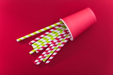 Kırmızı arka planda parlak renkli kokteyl pipeti. Geri dönüşüm ekosu konsepti. En az stil. Düz yat. üstte