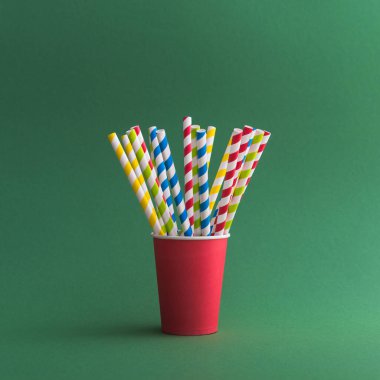 Yeşil arka planda kağıt bardakta parlak renkli kokteyl pipeti. Geri dönüşüm ekosu konsepti. pop sanat tarzı.