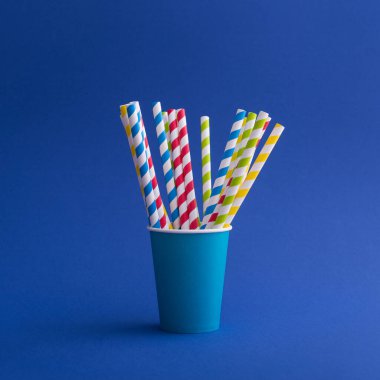 Mavi arka planda kağıt bardakta parlak renkli kokteyl pipeti. Geri dönüşüm ekosu konsepti. pop sanat tarzı.