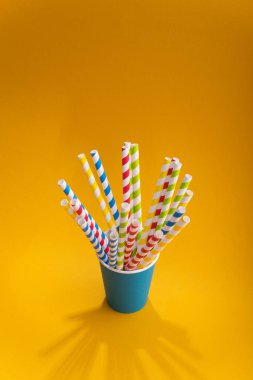Renkli arka planda kağıt bardakta parlak renkli kokteyl pipeti. Geri dönüşüm ekosu konsepti. pop sanat tarzı.