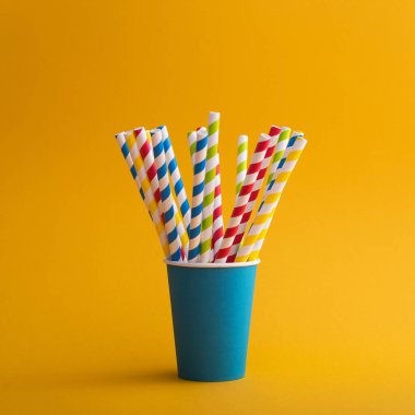 Renkli arka planda kağıt bardakta parlak renkli kokteyl pipeti. Geri dönüşüm ekosu konsepti. pop sanat tarzı.