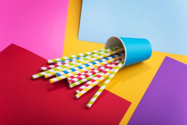 Renkli arka planda kağıt bardakta parlak renkli kokteyl pipeti. Geri dönüşüm ekosu konsepti. pop sanat tarzı.