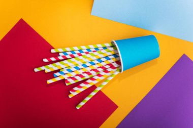 Renkli arka planda kağıt bardakta parlak renkli kokteyl pipeti. Geri dönüşüm ekosu konsepti. Pop sanat tarzı. Düz yat. üstte