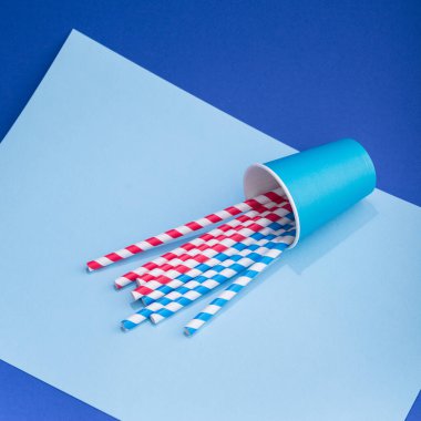 Mavi arka planda kağıt bardakta parlak renkli kokteyl pipeti. Geri dönüşüm ekosu konsepti. pop sanat tarzı.