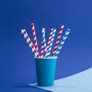 Mavi arka planda kağıt bardakta parlak renkli kokteyl pipeti. Geri dönüşüm ekosu konsepti. pop sanat tarzı.