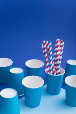 Mavi arka planda kağıt bardakta parlak renkli kokteyl pipeti. Geri dönüşüm ekosu konsepti. pop sanat tarzı.