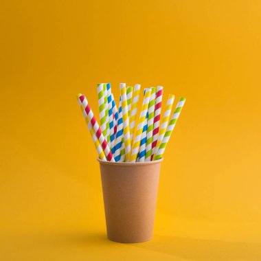 Sarı arka planda kağıt bardakta parlak renkli kokteyl pipeti. Geri dönüşüm ekosu konsepti. pop sanat tarzı.