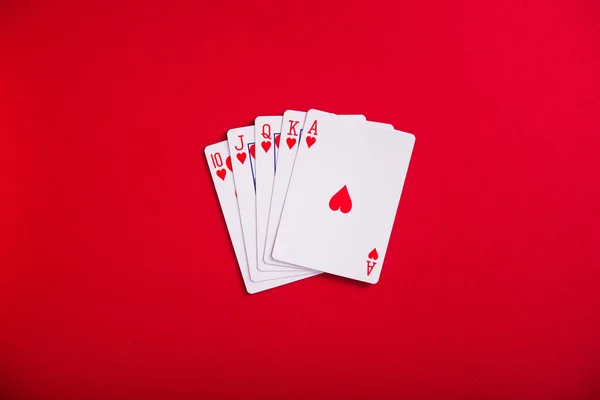 赤いテーブルの上のハートロイヤルフラッシュカード ポーカーカジノゲーム トップ表示 — ストック写真