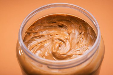 Sarı arka planda fıstık ezmeli açık kavanoz. Geleneksel Amerikan kahvaltısı.