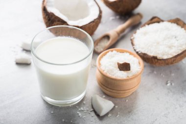 Bardakta taze hindistan cevizi sütü ve taş bir masada kırılmış meyve..