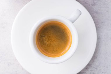 Beyaz seramik bardakta, gri bir fonda Espresso kahvesi. en üstteki görünüm