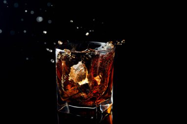 Viski, siyah bir arka planda cama sıçrar.