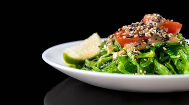 Siyah arka planda domates ve limonlu Chuka salatası.