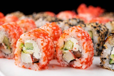Siyah arkaplanda suşi dürümleri var. Japon yemeği.