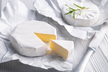 Ahşap beyaz arka planda taze çiğ camembert peyniri.