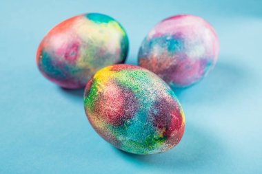 Mavi arka planda renkli uzay yumurtası olan Paskalya tatili konsepti.