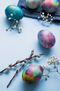 Mavi arka planda bahar çiçekleri olan mistik renkli yumurtalar. Paskalya tatili konsepti.