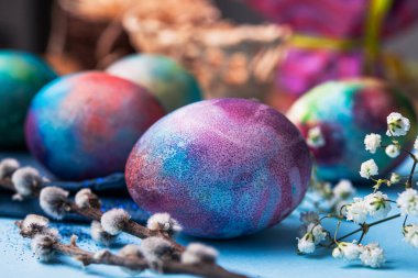 Mavi arka planda bahar çiçekleri olan mistik renkli yumurtalar. Paskalya tatili konsepti.