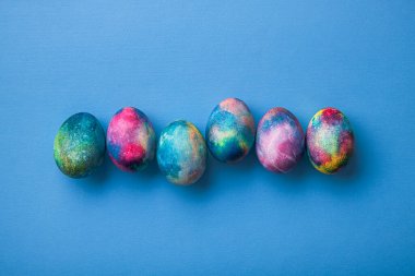 Mavi arka planda renkli uzay yumurtası olan Paskalya tatili konsepti. en üstteki görünüm