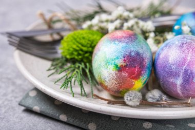 Taş zeminde renkli yumurta ve çiçeklerle dekoratif yuvarlak paskalya tabağı.